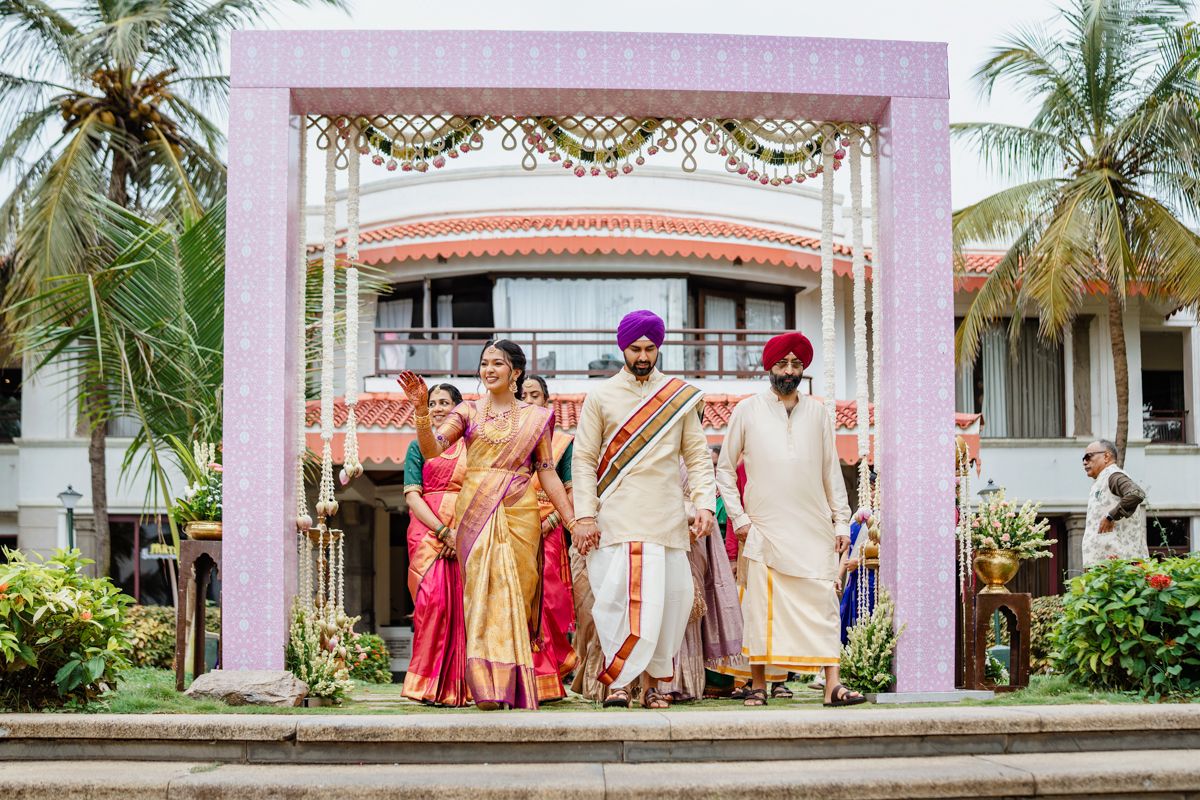 Traditional Indian wedding ceremony setup with pink decor and palm trees at an outdoor venue.