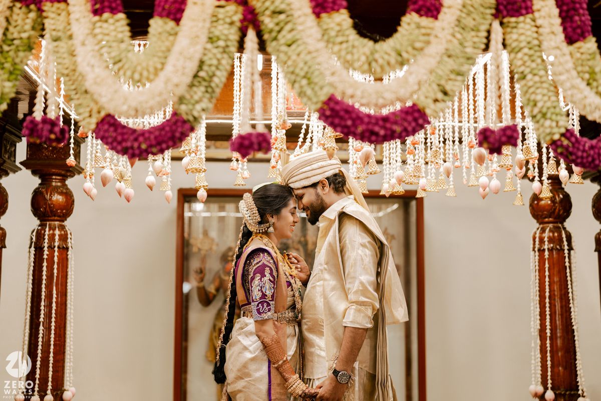 Elegant wedding mandap decorated with pink and white floral garlands and hanging crystals.