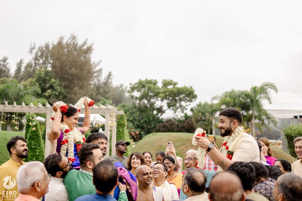 A crowd of wedding guests lifts their hands in celebration during an outdoor ceremony.