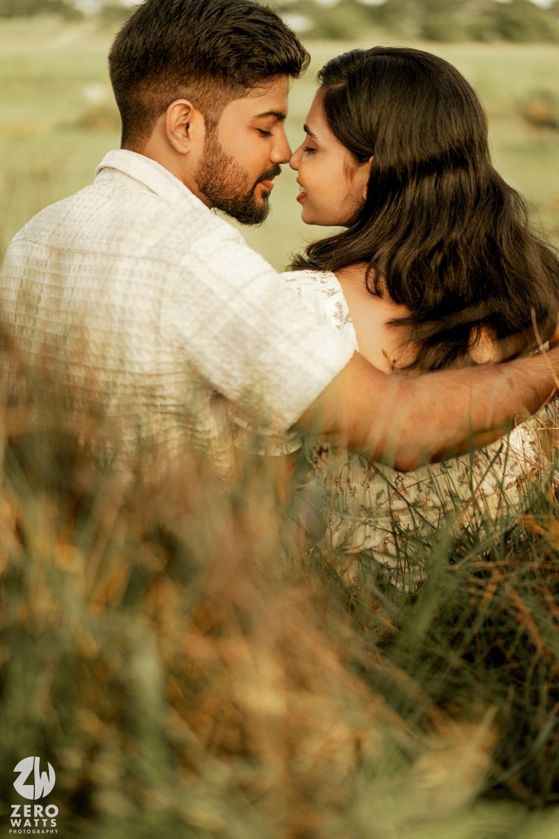 Romantic couple sharing intimate moments through tall grass in a natural outdoor setting.