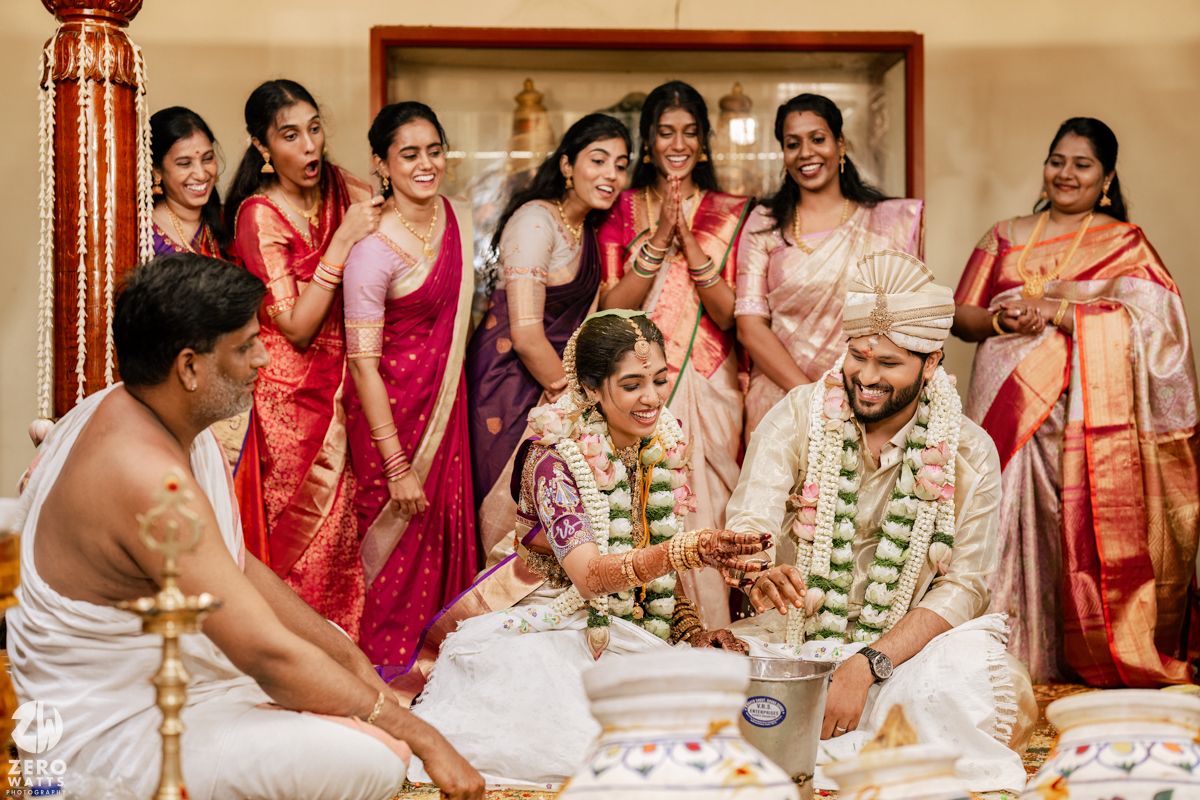 Traditional Indian wedding ceremony with participants seated on floor during ritual proceedings.