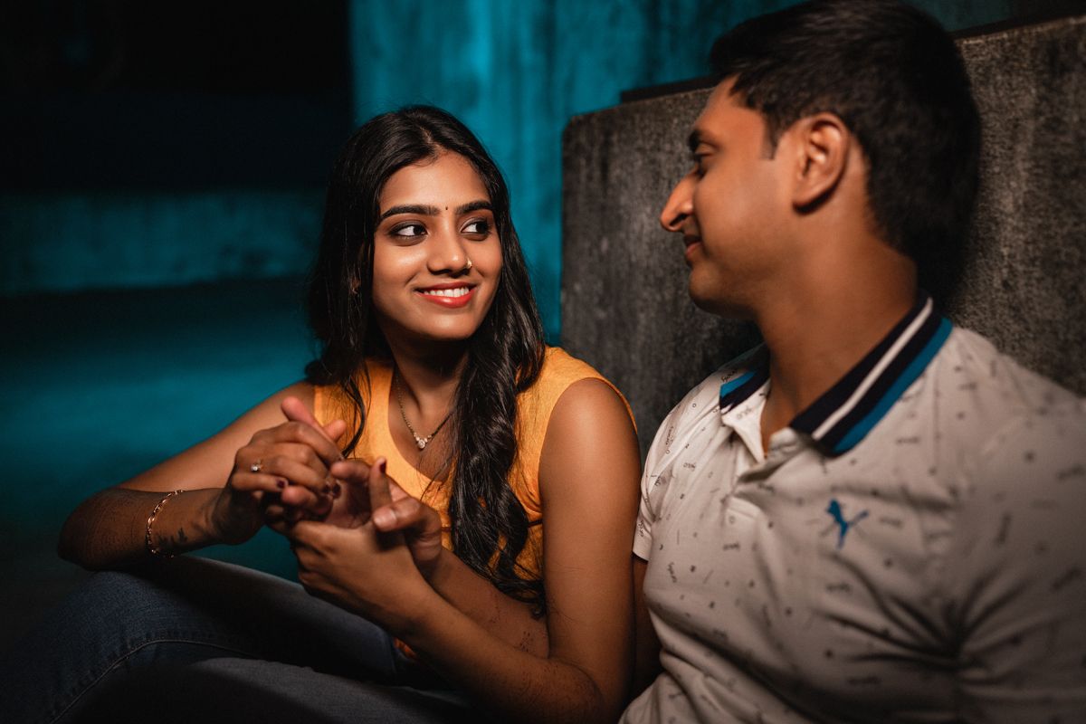 Couple sharing playful moments together in a dimly lit setting with blue tones.