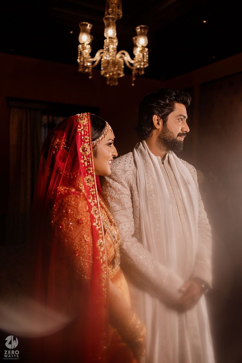 Artistic wedding photography with dramatic lighting and traditional attire in a dark setting.