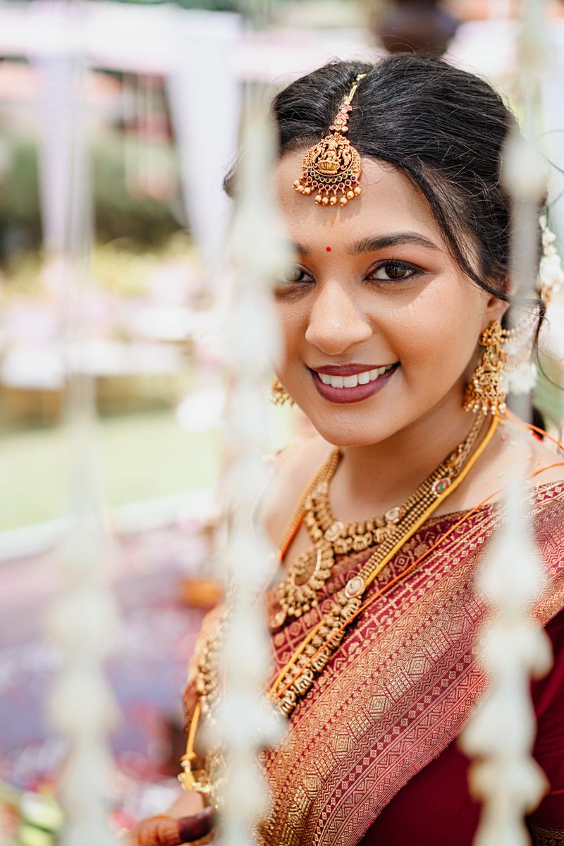 Close-up details of traditional Indian bridal jewelry and makeup in warm tones.