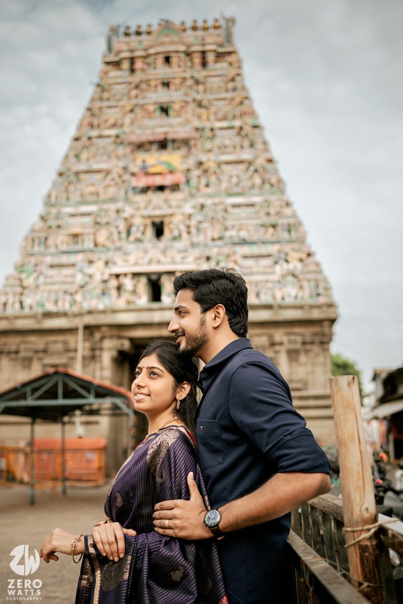 Romantic couple embraces in front of a majestic Hindu temple with intricate stone carvings.