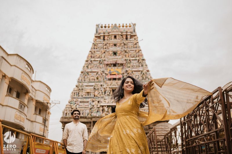 Ancient Hindu temple gopuram towers rise against cloudy sky with traditional architectural details.
