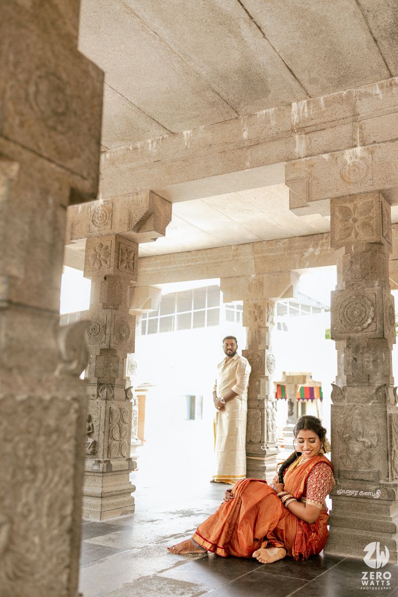 Ancient stone pillars and arches in a temple corridor create a serene architectural perspective in warm sepia tones.