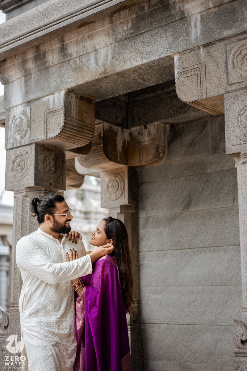 A romantic couple in traditional Indian attire share tender moments in a stone temple corridor.
