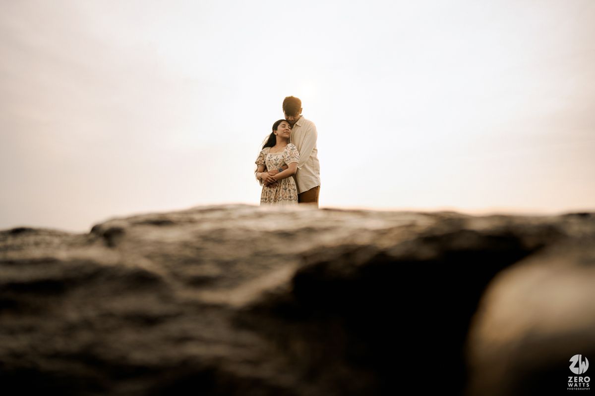 A silhouetted figure stands atop a rocky outcrop in sepia tones, creating a dramatic and moody composition.