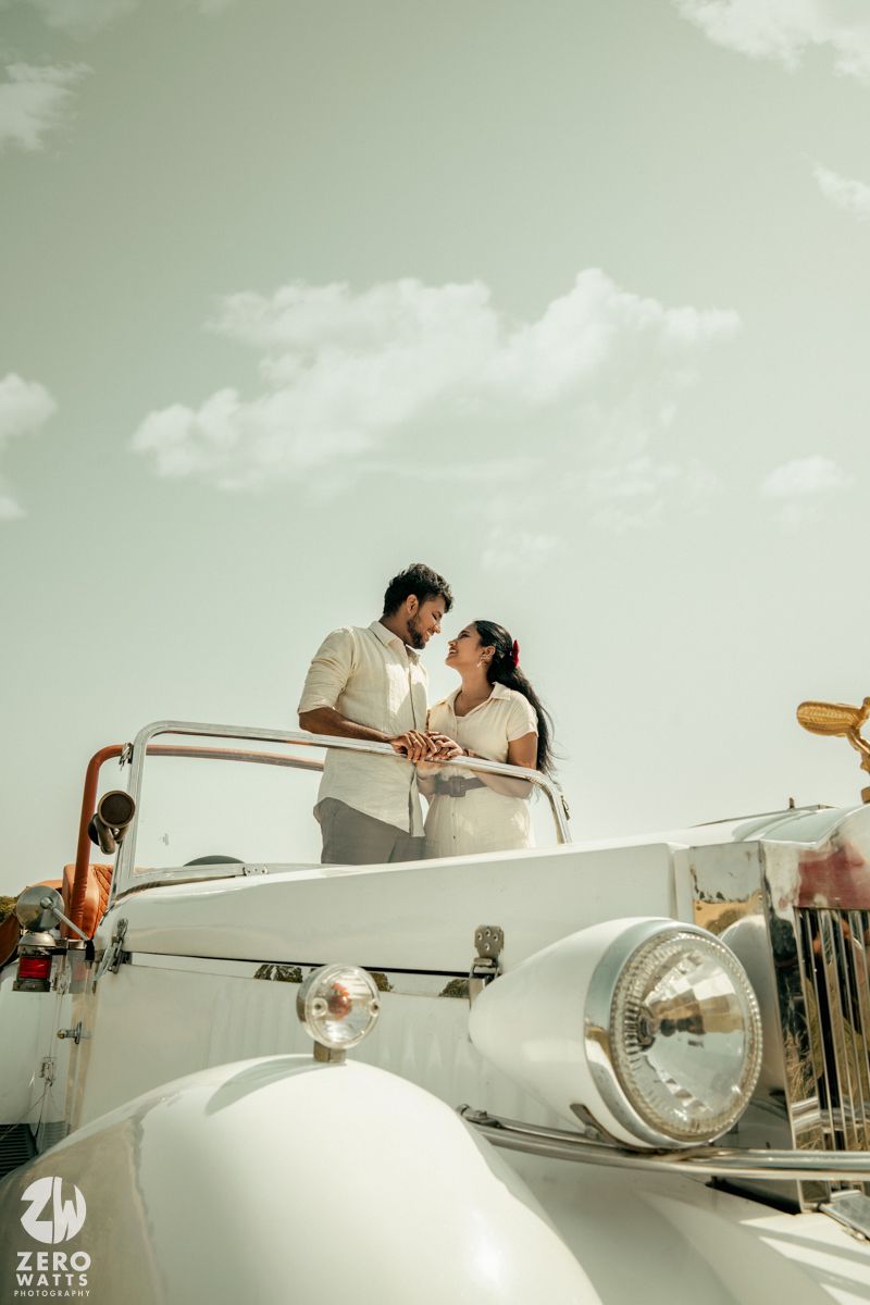 A pristine white classic car sits under cloudy skies with a dreamy vintage filter effect.