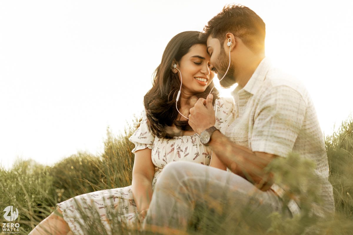 A romantic couple shares an intimate moment in a sunlit field during golden hour.