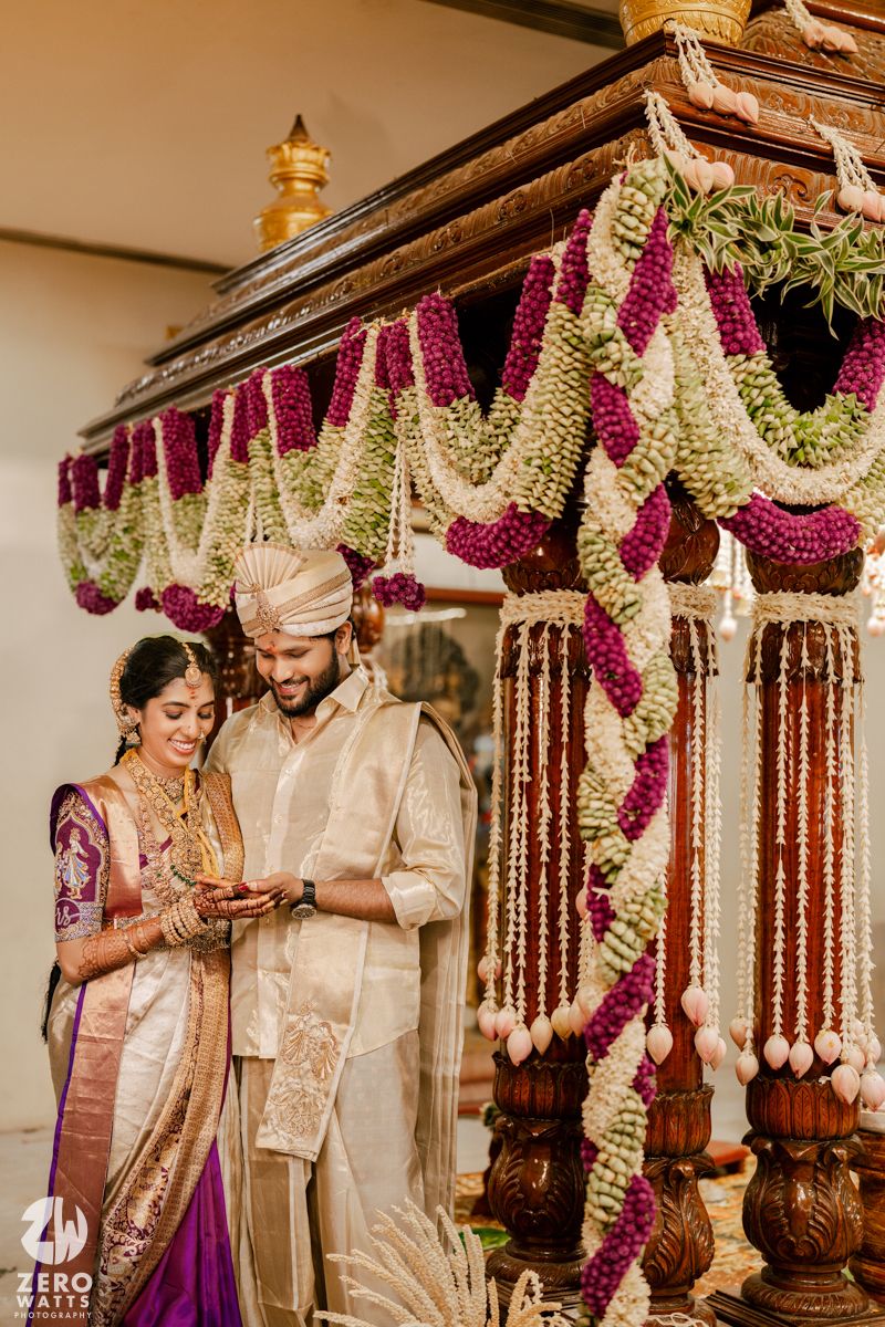 Elegant wedding mandap decorated with purple and white floral garlands and traditional wooden pillars.