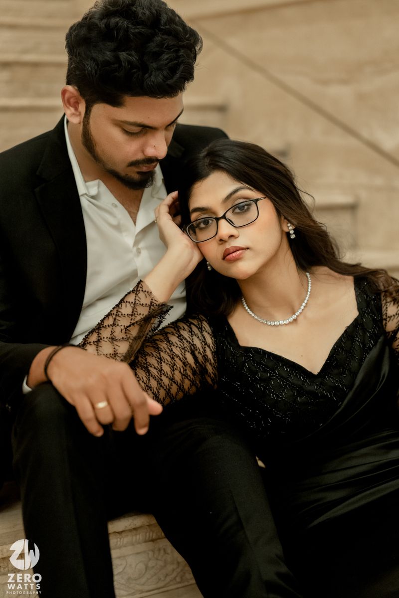 Romantic couple in black formal wear share intimate moment during indoor photoshoot.
