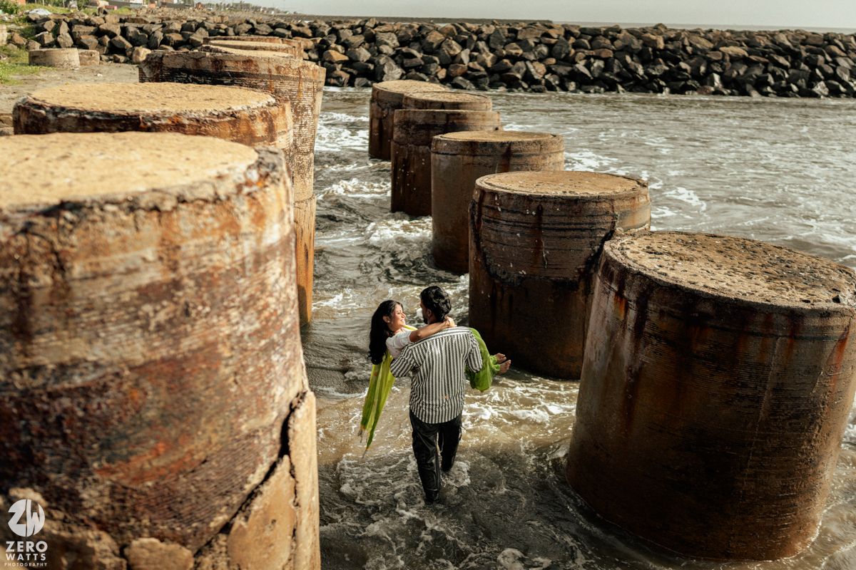 Rocky coastal landscape with large concrete pillars standing in the surf at low tide.