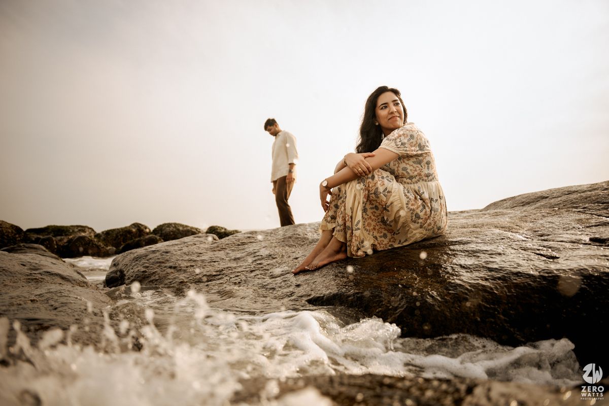 A romantic couple sits on coastal rocks at sunset in a dreamy sepia-toned photo series.