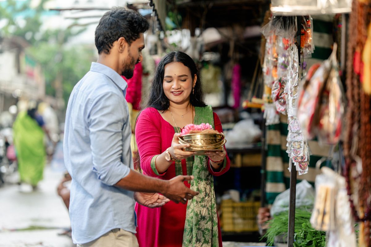 A couple examines decorative items at an outdoor market stall with traditional handicrafts.