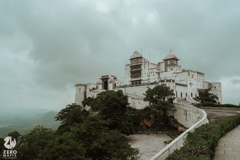 Majestic view of Monsoon Palace perched on hilltop under cloudy skies in Udaipur, India.