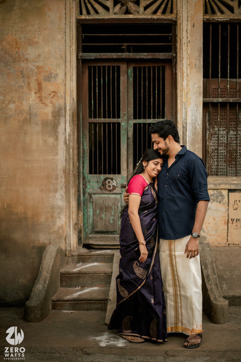 A couple shares intimate moments against vintage colonial architecture with weathered walls and pillars.