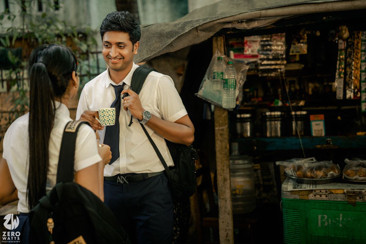 Student with backpack stands near a small shop or vendor stall.