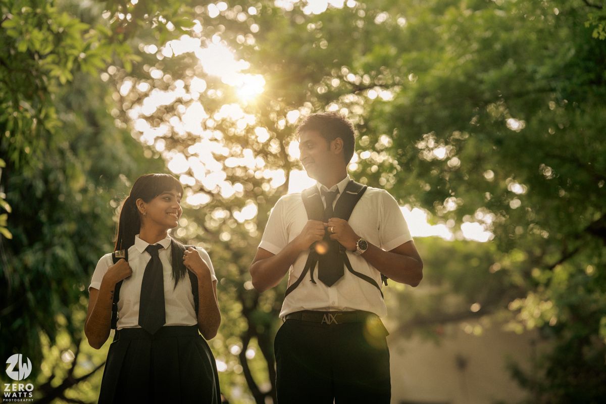 Students in uniforms sharing a moment outdoors with golden sunlight filtering through trees.