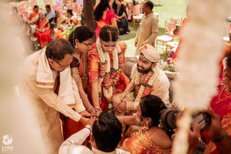 South Indian wedding ceremony with bride, groom, and family gathered under decorated mandap.