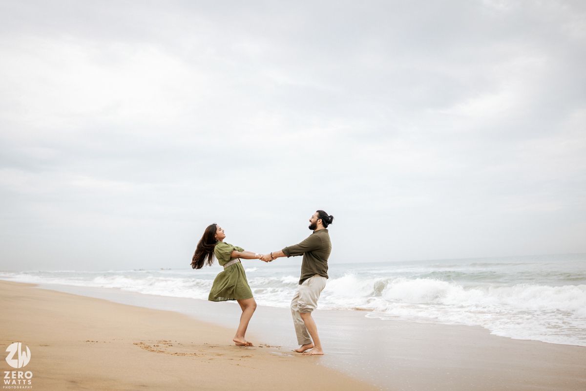 Two people playfully interacting on a foggy beach near the ocean waves.