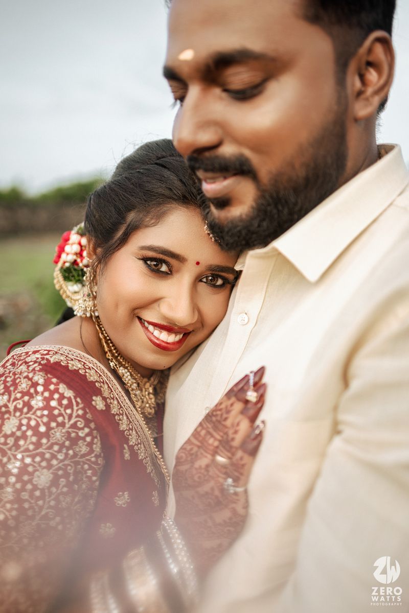 A couple in traditional Indian wedding attire share an intimate moment during their wedding photoshoot.
