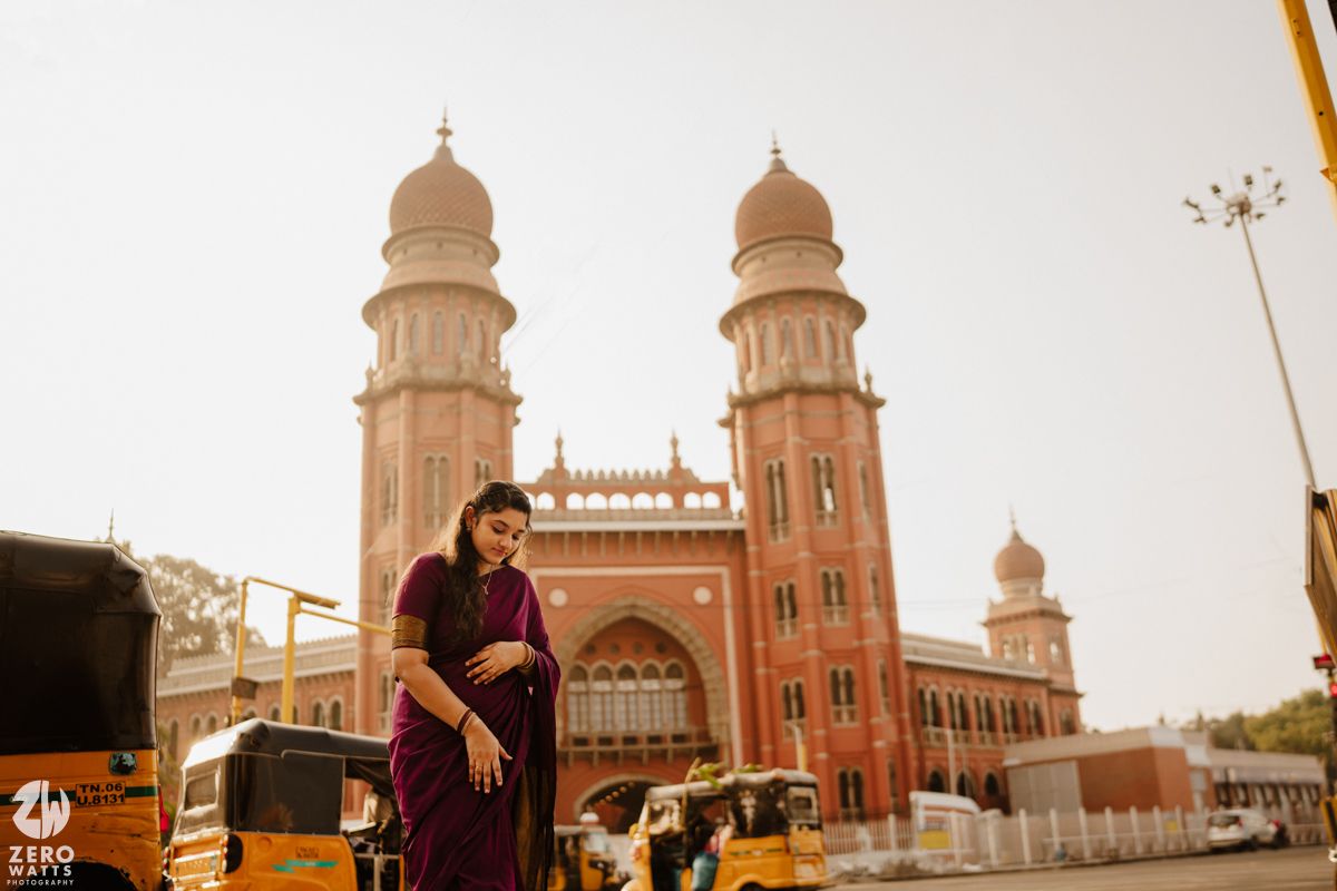 Couple posing in front of majestic Indo-Gothic architecture during sunset.