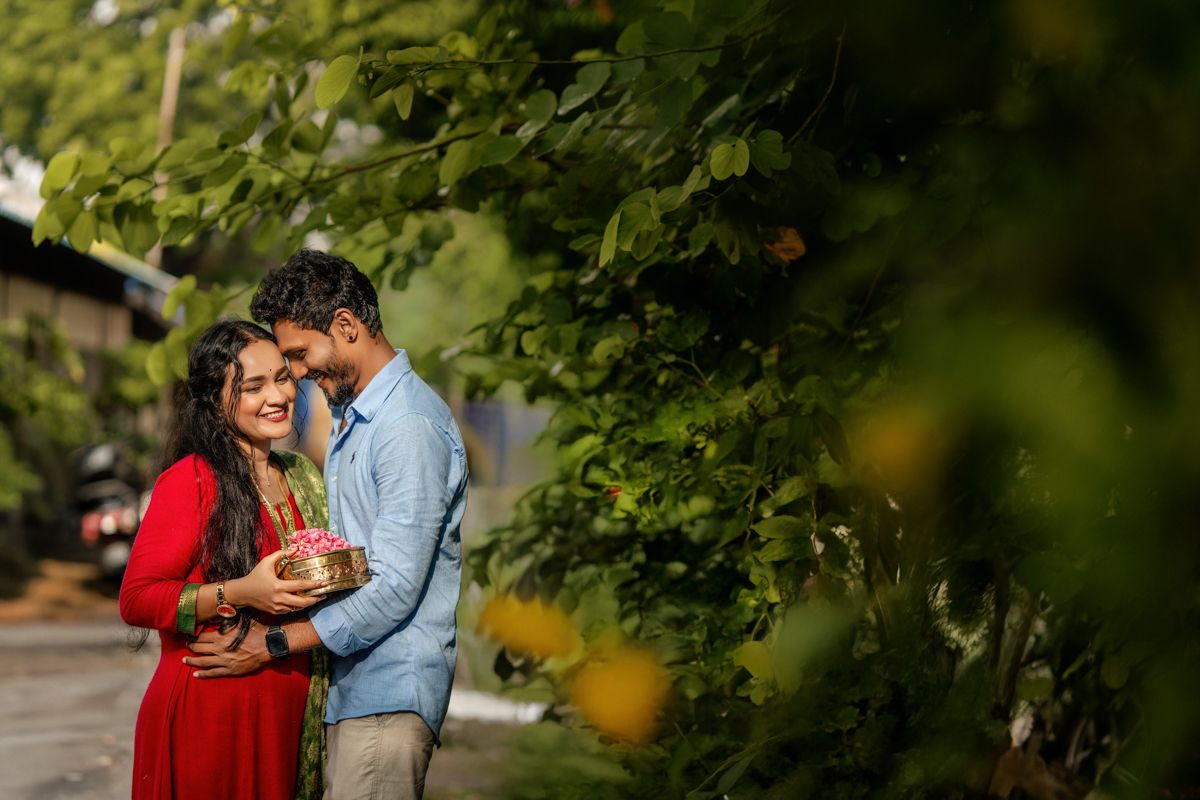 Intimate outdoor portrait among green foliage with natural sunlight filtering through trees.