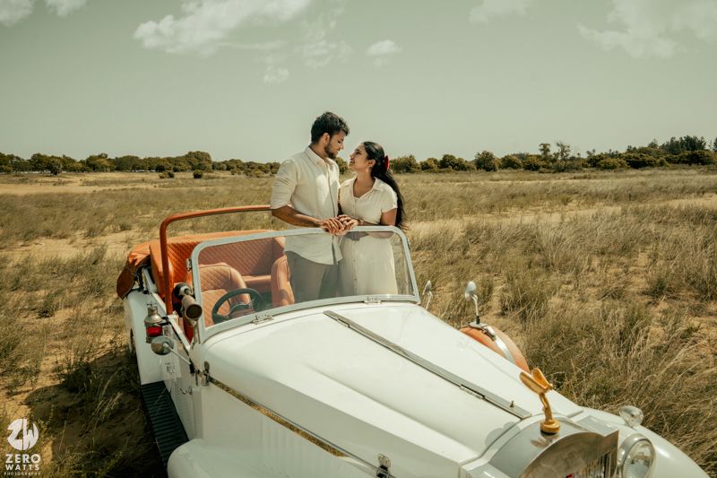 A pristine white classic car photographed in a golden savanna landscape.