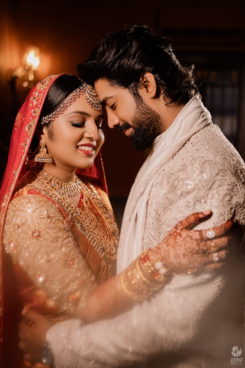 Romantic Indian wedding couple in traditional attire sharing intimate moments in warm lighting.