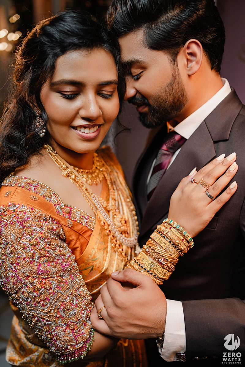 Romantic wedding portrait with ornate gold jewelry and embellished orange traditional attire.