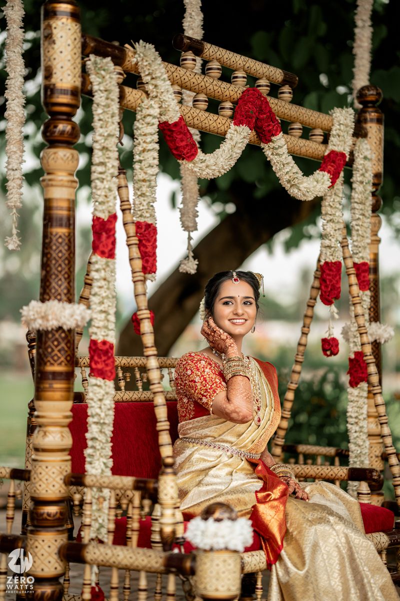 Traditional South Indian wedding ceremony setup with ornate wooden pillars decorated with white and red floral garlands.