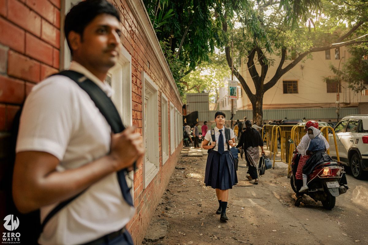 Students walking and chatting in a school courtyard with brick walls and trees in warm afternoon light.