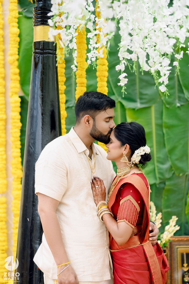 Wedding ceremony setup with yellow marigold garlands and white floral decorations against a green backdrop.