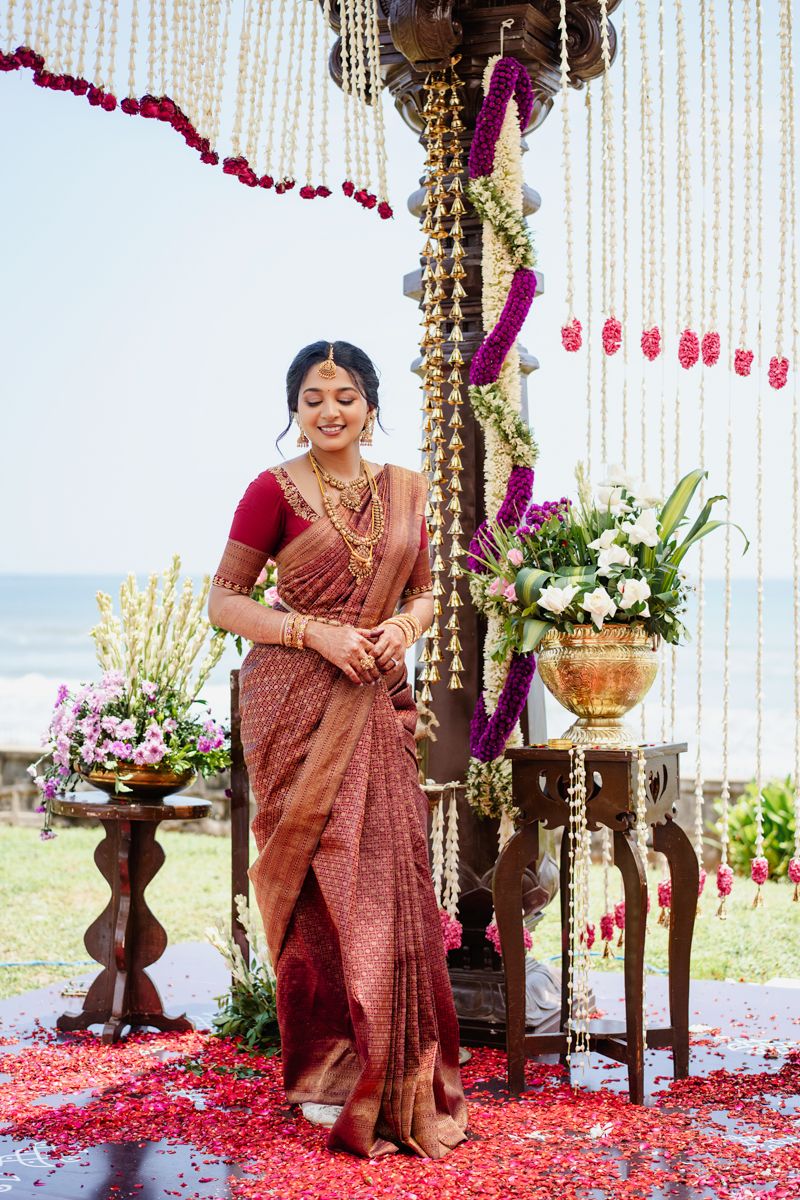 Traditional Indian wedding ceremony space with red rose petals and hanging floral decorations.