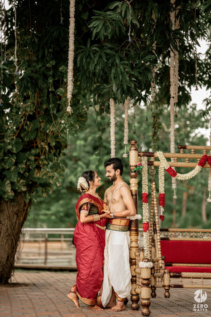 Romantic outdoor photoshoot with couple in traditional South Indian wedding attire among trees.