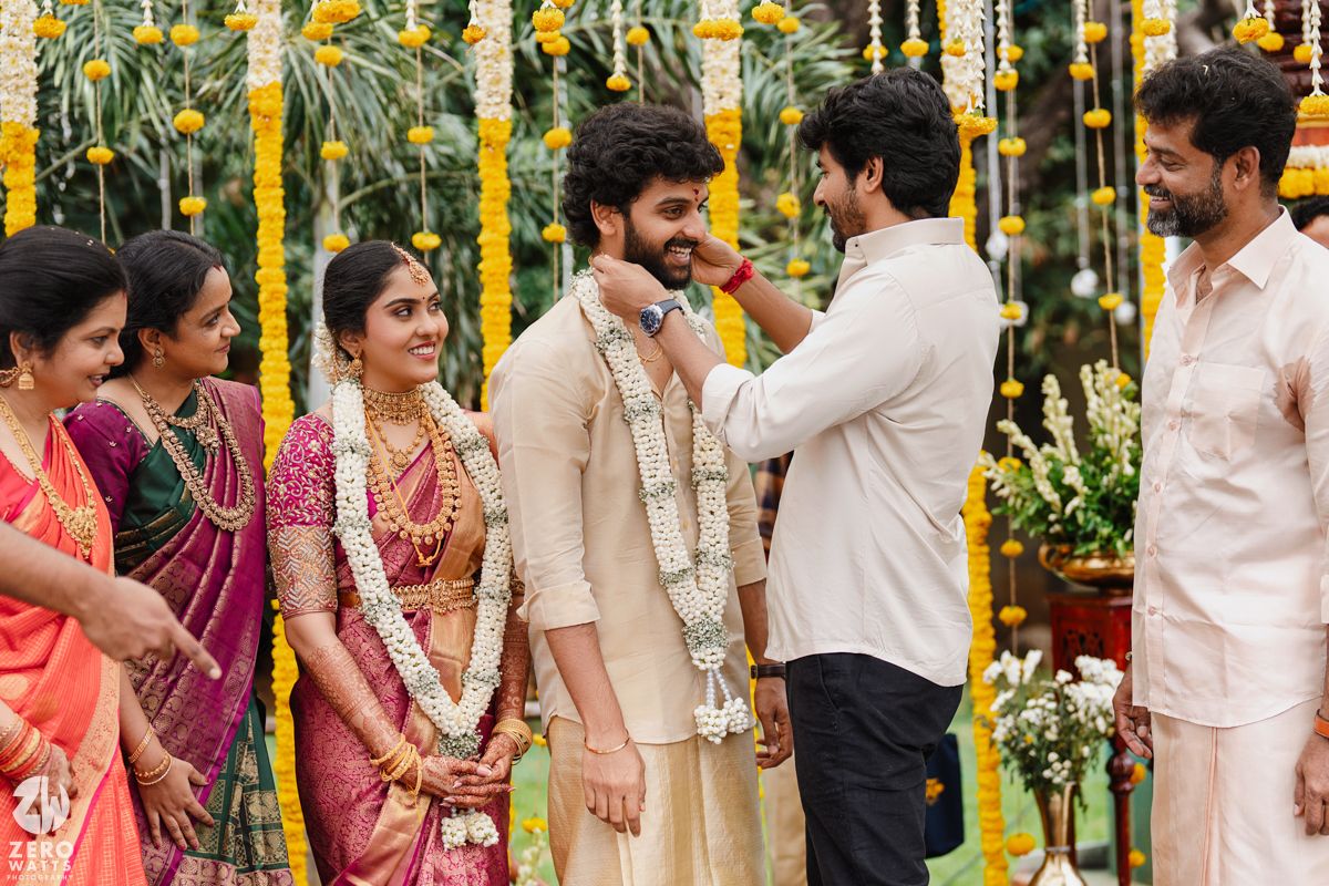 Outdoor Indian wedding ceremony with yellow marigold decorations and guests in traditional clothing.