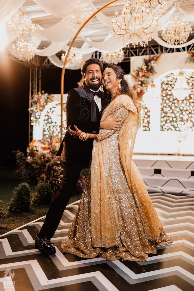 A couple in traditional wedding attire share joyful moments on a patterned dance floor.