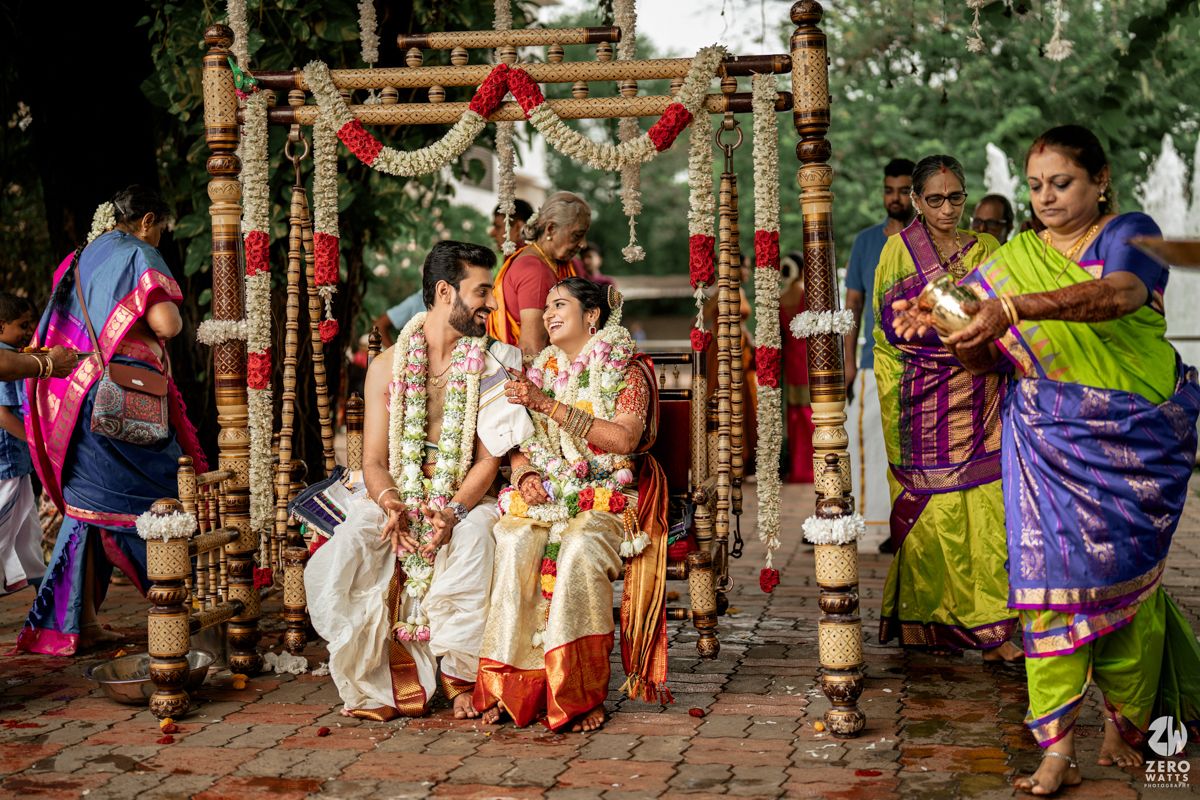 Traditional Indian wedding ceremony with decorative red and gold elements in an outdoor garden setting.