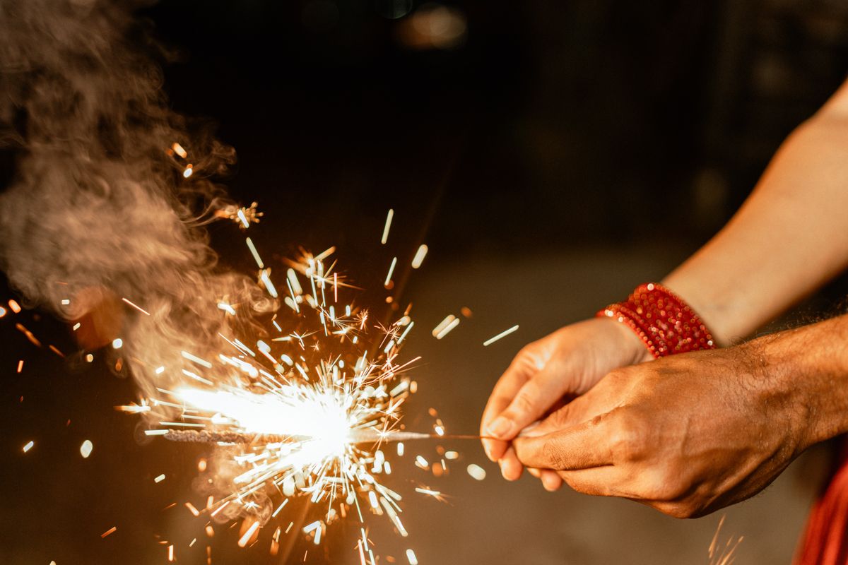 A sparkler burns brightly creating a trail of light against a dark background.