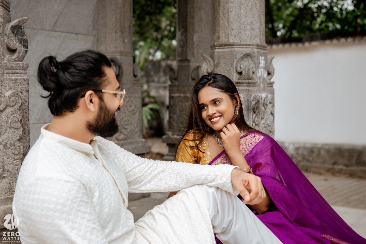Couple in traditional Indian attire sharing a joyful moment at a temple setting.