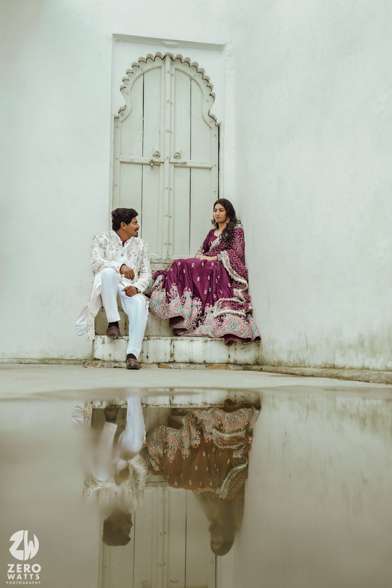 Artistic reflection shot in puddle showing ornate white doorway with decorative arch details.