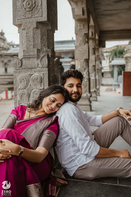 A romantic couple poses beneath historic stone columns, creating an intimate moment.