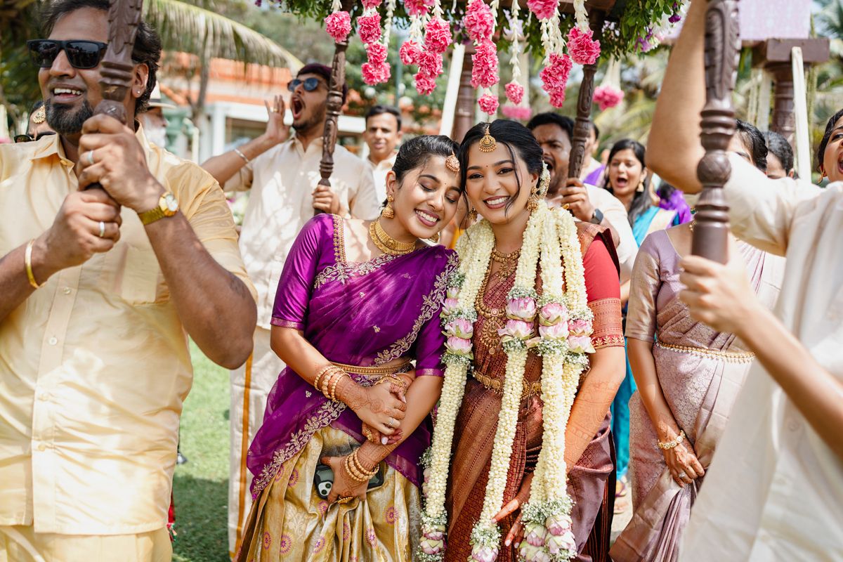 Colorful celebration at an Indian wedding ceremony with guests dancing and throwing flower petals in joyous festivities.