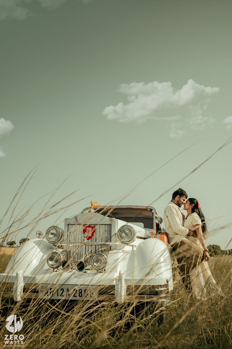 A romantic vintage-themed photoshoot featuring a classic white car in a field of tall grass.