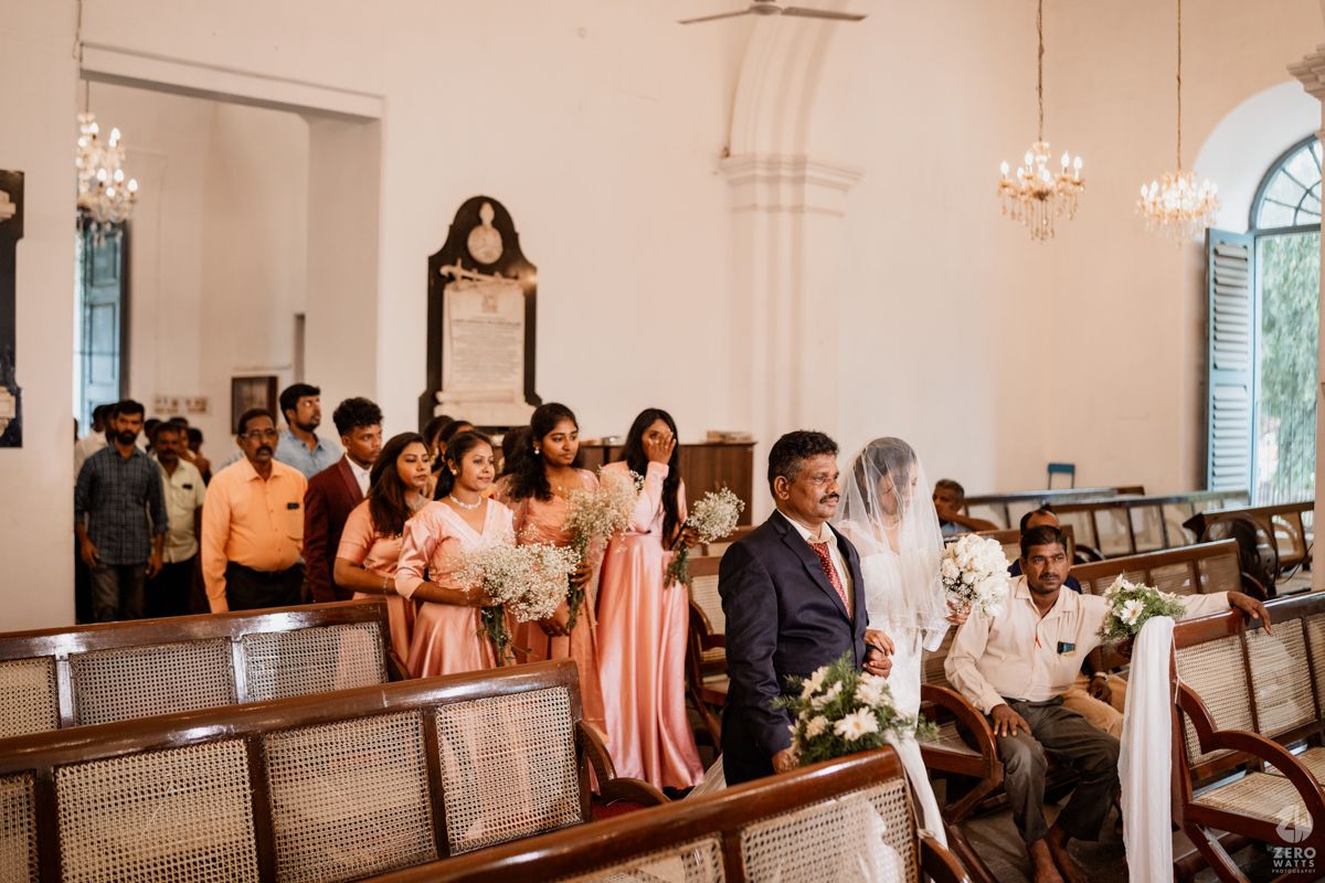 Interior view of a traditional church with wooden pews and chandeliers during a wedding ceremony.
