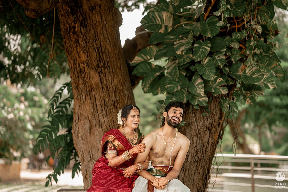 Romantic outdoor couple photoshoot under a lush green tree canopy in traditional Indian attire.