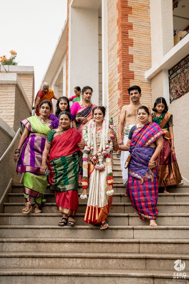 Wedding guests in colorful traditional Indian attire seated on stone steps for a group photo.