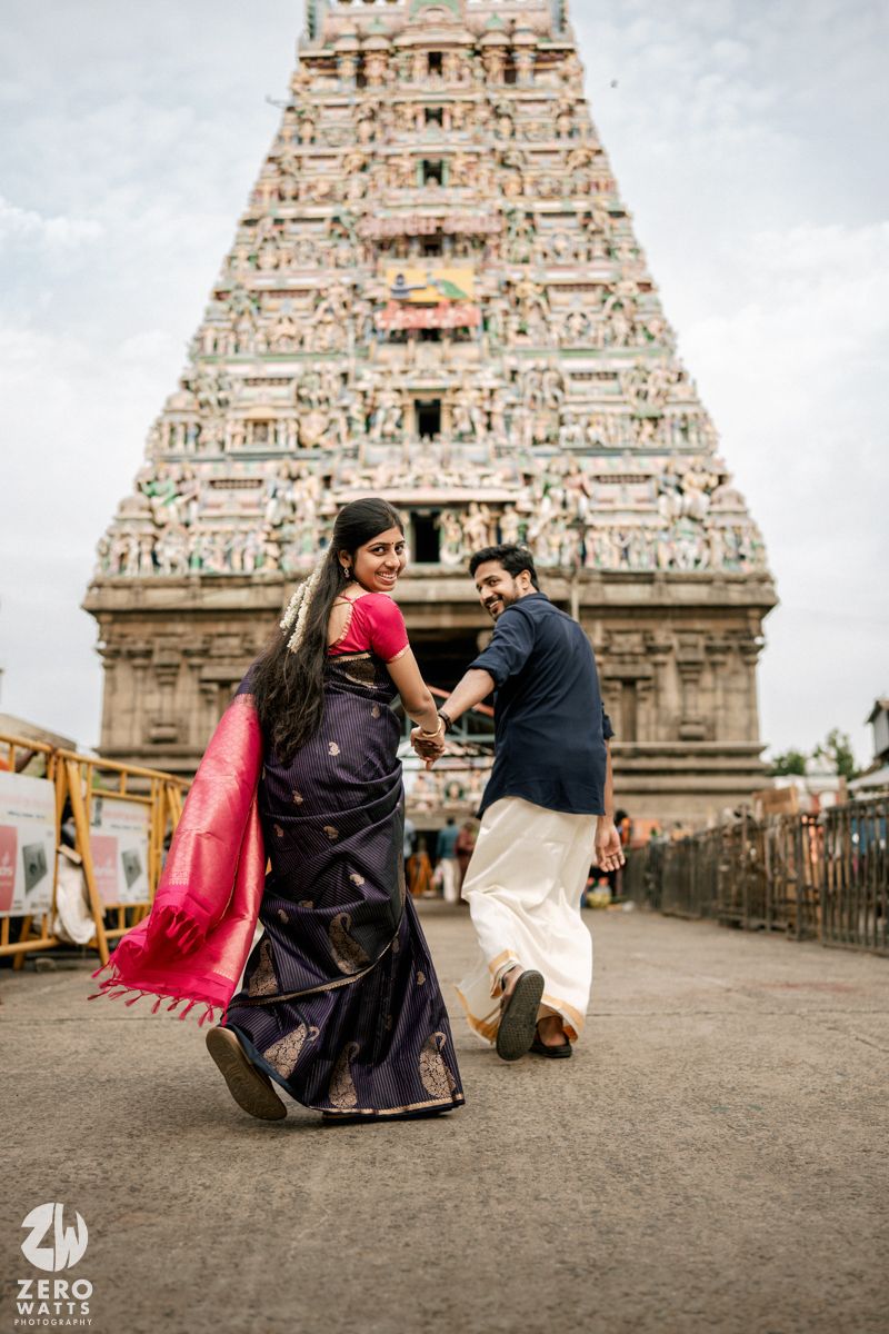 Couple poses in front of an intricately carved South Indian temple gopuram during a photo session.